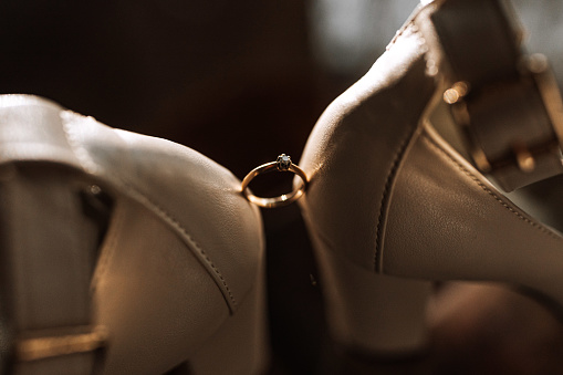 elegant women's ring on a dark background is set between women's shoes