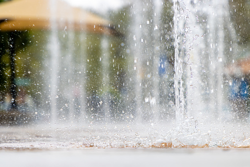 Water streams and sprays at a children's splash pad in a downtown park.