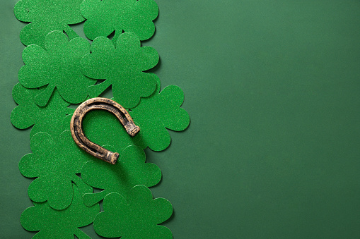 St. Patrick's day border with clover leaf and horseshoe on green background. View from above. Copy space.
