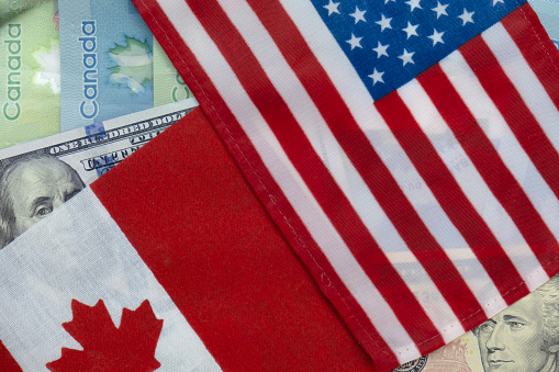 United States and Canadian flags on US dollar and Canadian loonie currencies. Flat lay. Concept of vacation, trade, finance, travel, currency exchange and business cooperation. Macro close up selective focus high quality photo