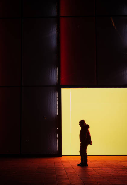 sylwetka dorosłego mężczyzny w zimowym ubraniu na ulicy pod ścianą w nocy - fashionable contemporary cool front view zdjęcia i obrazy z banku zdjęć