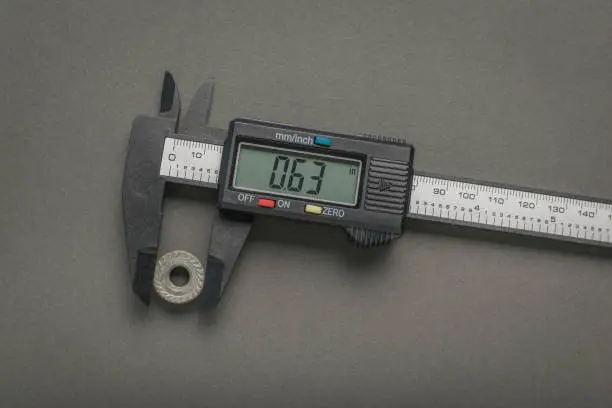 Photo of Measuring the nut with an electronic vernier caliper on a gray background.