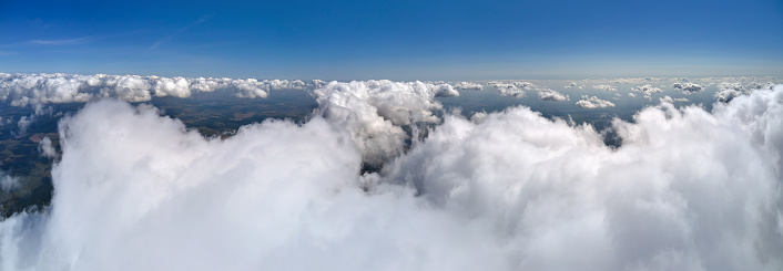 Aerial view from airplane window at high altitude of earth covered with puffy cumulus clouds forming before rainstorm.