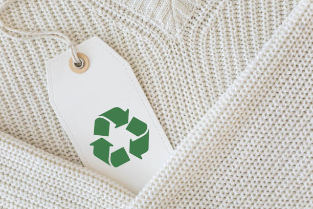 istock White knitted clothing with a white label featuring the recycling symbol. 2062056430