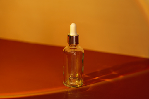 Glass bottle with pipette under yellow light. High quality photo