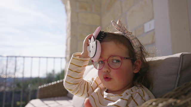 SLO MO Cute Little Girl in Eyeglasses Brushing her Hair while Relaxing on Balcony at Holiday Villa