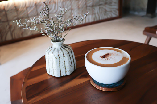 hot coffee, cappuccino coffee or latte coffee or flat white or mocha coffee and caspia flower in a vase on the table