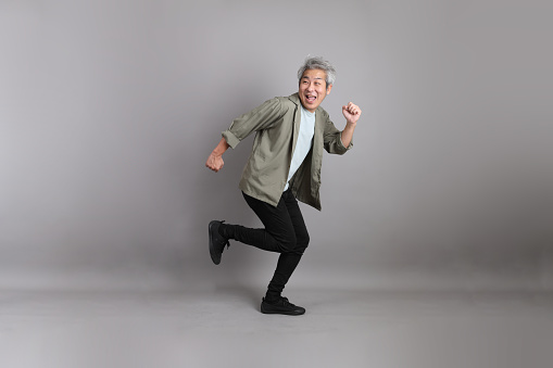 The 40s Asian man with smart casual clothes standing on the grey background.