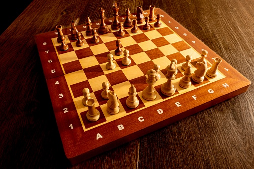Chessboard made of wood with pieces forming the Queen’s gambit opening