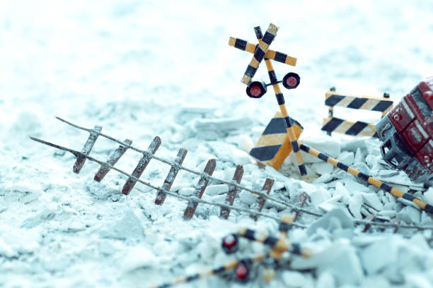 Closed railway crossing gate and a red warning light with a freight train in background