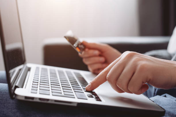 Selective focus of female hands of person entering credit card data laptop computer during pay for internet shopping online sitting alone on sofa at home stock photo