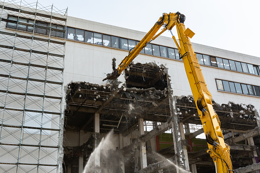 A building demolition site where work is carried out by many people and machines such as power shovels.