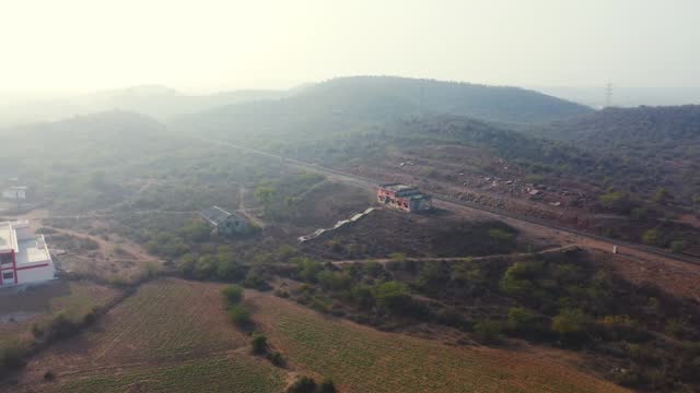 Aerial Drone shot of a abandoned railway station building with a hilly village landscape in background in Madhya Pradesh India