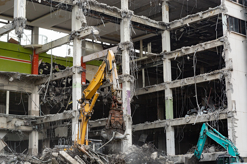 A building demolition site where work is carried out by many people and machines such as power shovels.