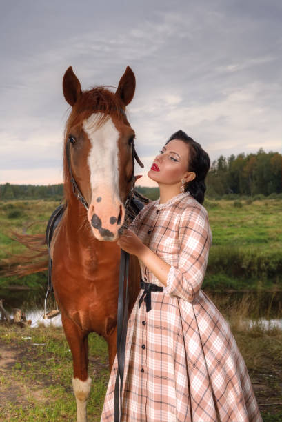 Young beautiful woman in a retro dress next to a horse.