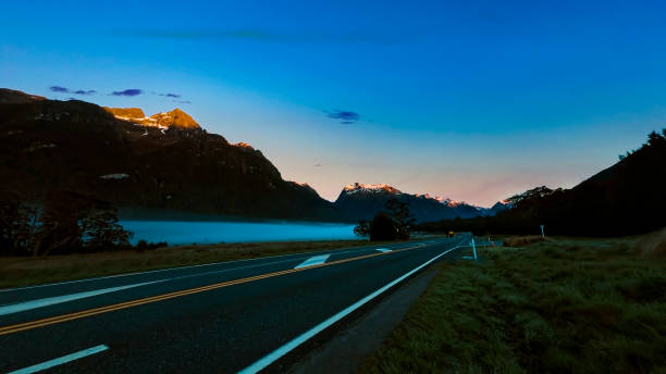 the road trip view of  travel with mountain view of autumn scene and  foggy in the morning with sunrise sky scene at fiordland national park - sunrise new zealand mountain range mountain - fotografias e filmes do acervo