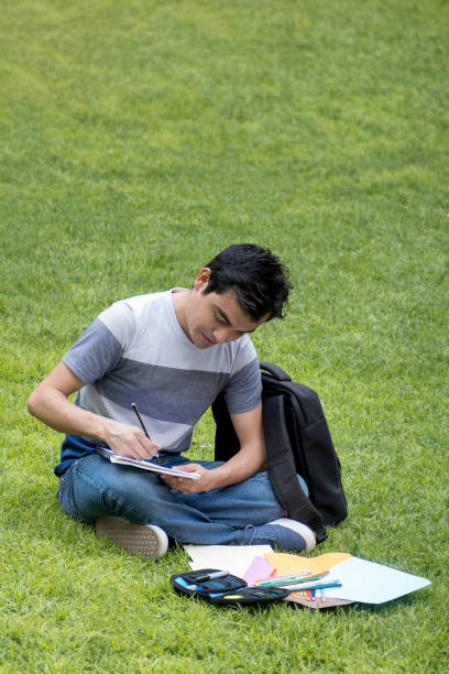 istock A male student sitting on the grass writing in a notepad 2062399786