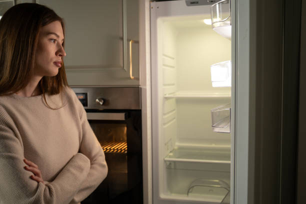 istock Young Woman Standing Before an Open Empty Refrigerator in a Modern Kitchen 2062416047