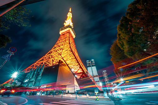 Tokyo Tower illuminated at night with dynamic light trails from traffic, showcasing the bustling city life of Tokyo.