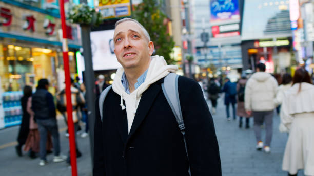 istock Middle Aged White Man Looking up while Exploring Shinjuku, Japan 2062428612