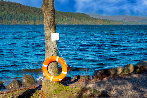 An orange life belt at the side of Lake Windermere in the English Lake District, Cumbria, North West England, UK.