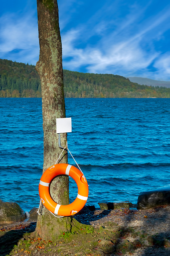 An orange life belt at the side of Lake Windermere in the English Lake District, Cumbria, North West England, UK.