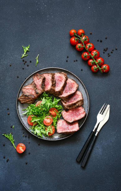 istock Grilled beef with arugula salad and tomatos on a dark background 2062473957