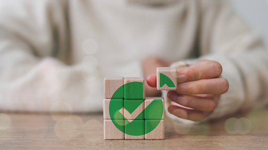 Wooden cube with a green checkmark icon. Corporate regulatory and compliance. Goals achievement and business success. Task completion. Ethical corporate. Do the right thing. Quality and ISO symbol.