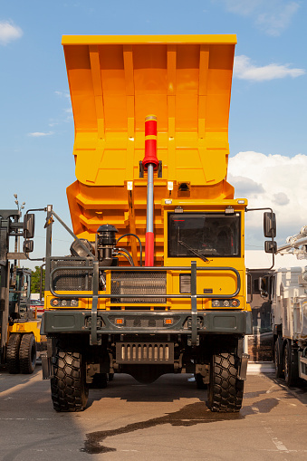 An orange mining dump truck with a raised body is parked.