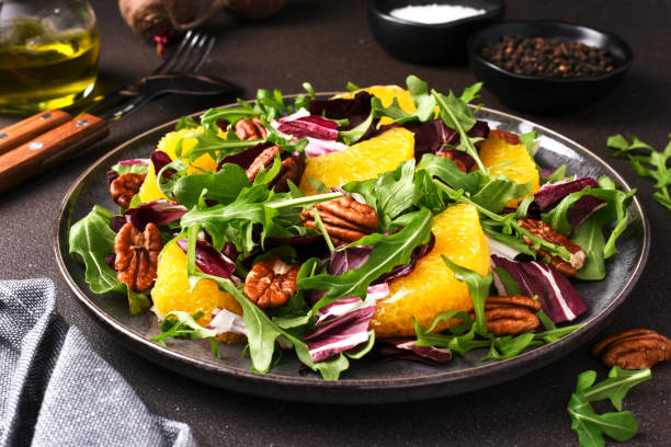 arugula, orange and pecan salad. radicchio salad on brown background - organi imagens e fotografias de stock