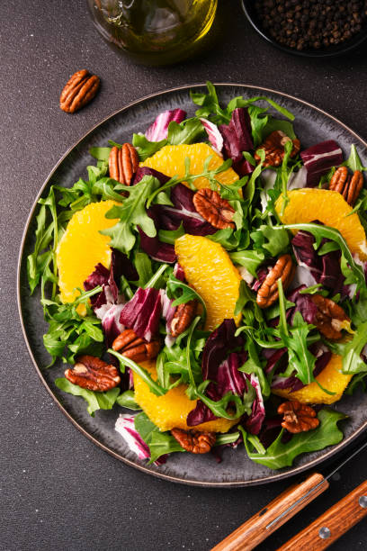 arugula, orange and pecan salad. radicchio salad on brown background - organi imagens e fotografias de stock