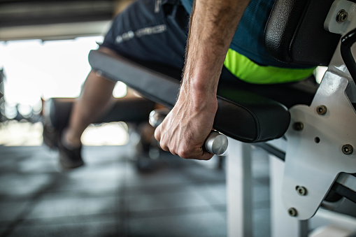 Close up of unrecognizable male athlete exercising leg strength on a machine in a health club.
