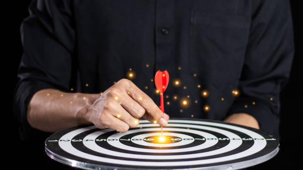 istock Businessman throwing red arrow dart to  target dart board. Setup objectives and target for business investment concept. business investment objective concept Marketing strategies and goals for success 2062552132