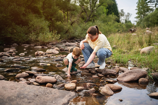 Mom and son playing on the shallow mountain river.