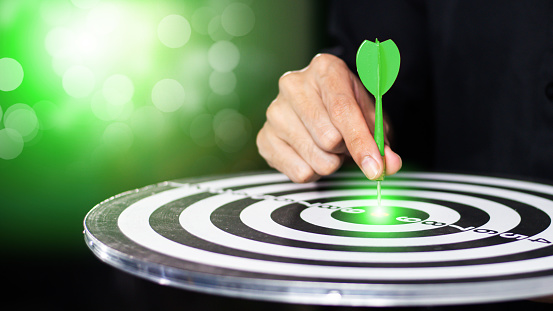 Businessman throwing green arrow dart to  target dart board. ESG environment social governance investment business concept, green business, carbon reduce, social media, financial success