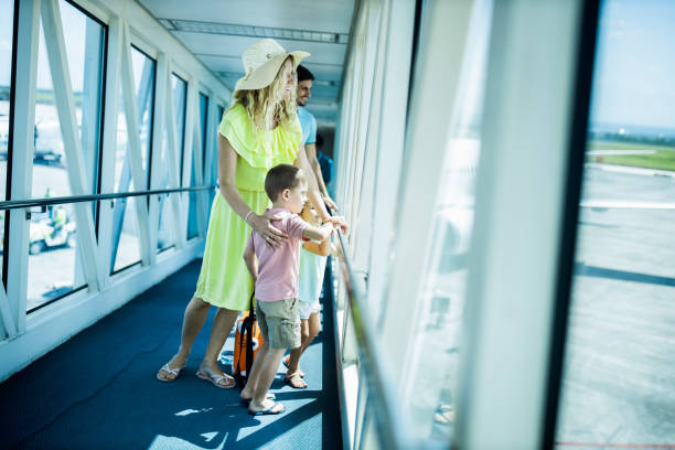 istock Young happy family looking through window from airport terminal. 2062563041