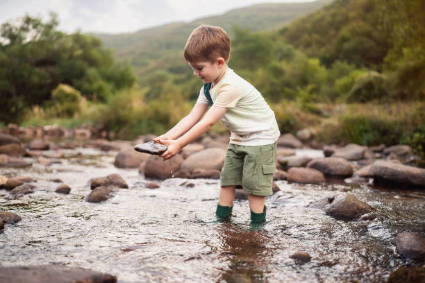 istock Happy little boy playing in the shallow mountain river 2062564635