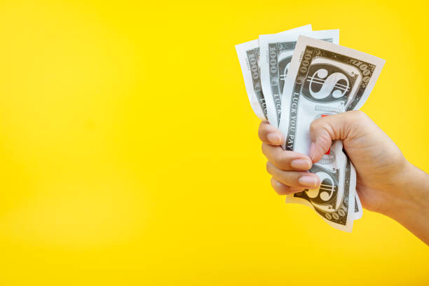 istock Female hands holding banknotes on a yellow background. 2062568398