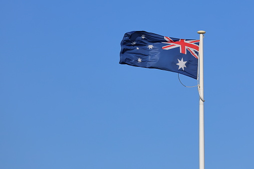 The Australian flying in the wind against a clear blue sky, with plenty of copy space