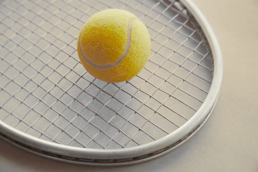 yellow tennis ball lies on a racket for playing big tennis close-up