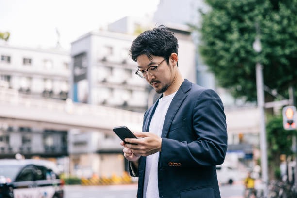 istock Japanese businessman sending a work email with smartphone on the go 2062596858