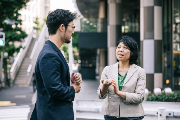 istock Two Japanese colleagues chat together on the sidewalk. 2062596862