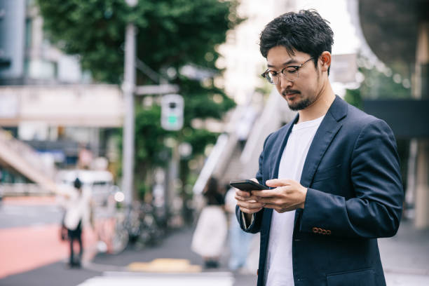 istock Japanese businessman sending a work email with smartphone on the go 2062597409