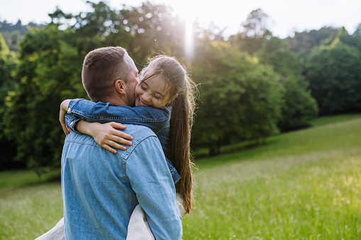 Father with daughter, hugging at meadow, running, having fun. Concept of fathers's Day and fatherly love.