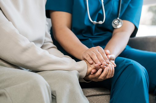 A female nurse caregiver holds hands to encourage and comfort an elderly woman. For care and trust in nursing homes for people of retirement age Caregiver helping elderly woman provides medical advice