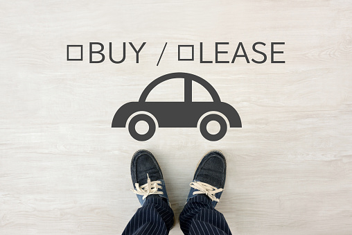 Man’s feet and car pictogram with BUY / LEASE word