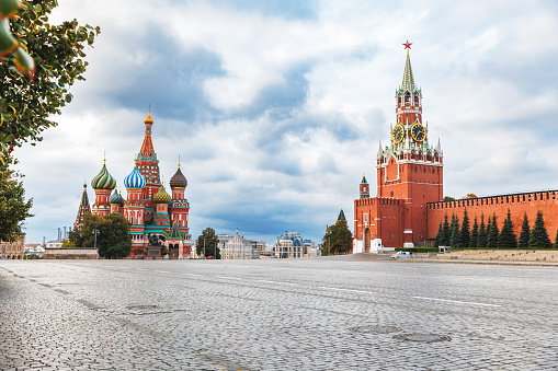 Saint Basil cathedral and Spasskaya Tower among new year festive decorations on Red Square in Moscow. Christmas fair in Kremlin of Russia at evening while snow falling