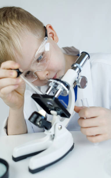 istock Child chemist. Teacher shows a visual experiment. A science mentor teaches an experimental approach. Microscope, petri dish, pipettes, books. Practical work in chemistry or physics. Laboratory work 2062667031