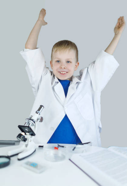 Practical work in chemistry or physics. Laboratory work. Child chemist. Teacher shows a visual experiment. A science mentor teaches an experimental approach. Microscope, petri dish, pipettes, books.