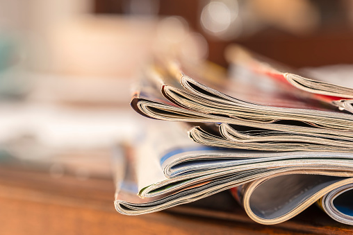 Pile of old newspapers magazines on toned blur background